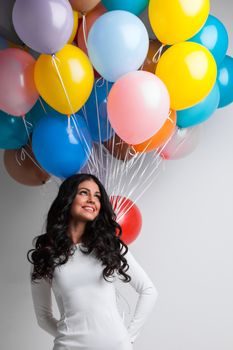 Young pretty woman in white dress with color balloons on white background with copy space for text