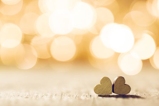 Two handmade wooden hearts on beautiful golden bokeh background. Vintage style. Love Valentine's Day concept.