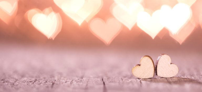 Two handmade wooden hearts on beautiful pink bokeh background. Vintage style. Love Valentine's Day concept.