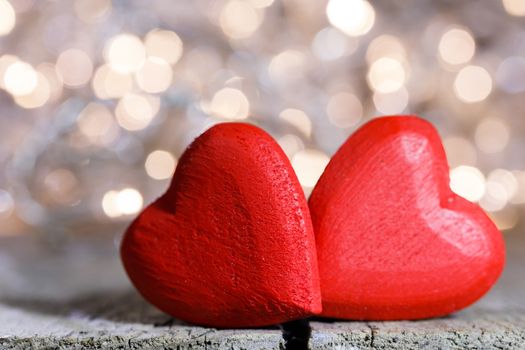 Two red wooden hearts symbol of love on background with beautiful bokeh party lights, Saint Valentine Day celebration