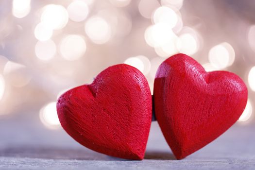 Two red wooden hearts symbol of love on background with beautiful bokeh party lights, Saint Valentine Day celebration