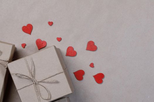 Box with gifts wrapped in brown craft paper and red paper hearts Valentines day concept