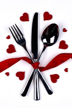 Cutlery set tied with silk ribbon and hearts on white background Valentine day dinner concept