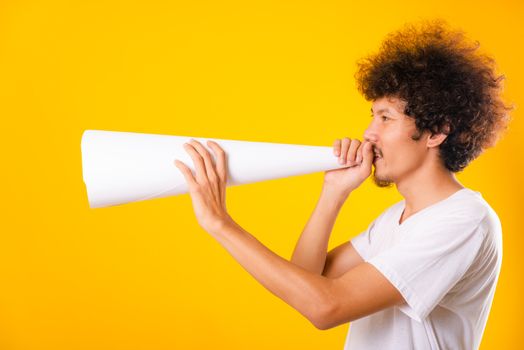 Asian handsome man with curly hair he announcing or spreading news using white speaker paper isolate on yellow background