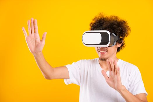 Asian handsome man with curly hair he using virtual reality headset or VR glass isolate on yellow background