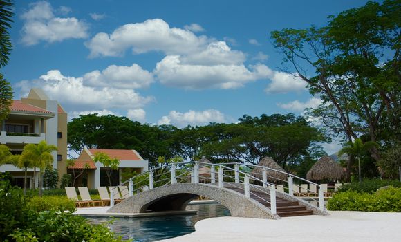 A white bridge over a placid blue swimming pool