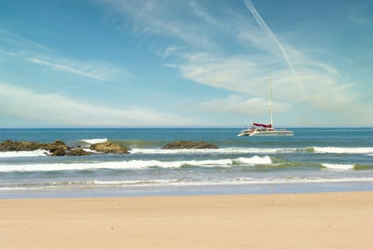 A nice catamaran anchored past the rocks off the coast