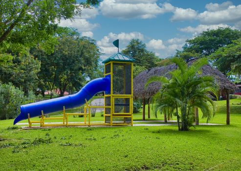 A park playground with a blue sliding board.