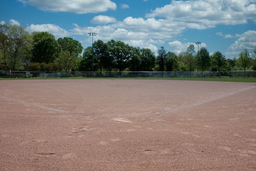 A view of an empty softball or baseball field from behind home plate