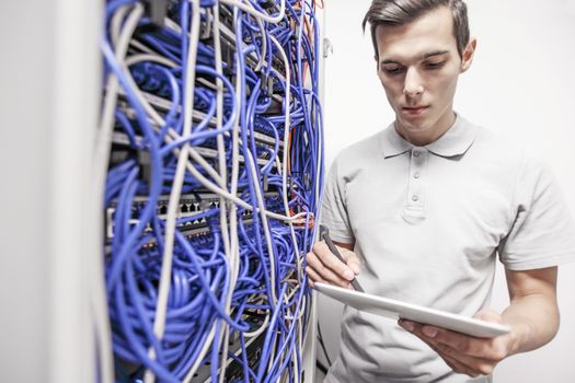 Man using tablet pc beside servers in data center internet technology concept