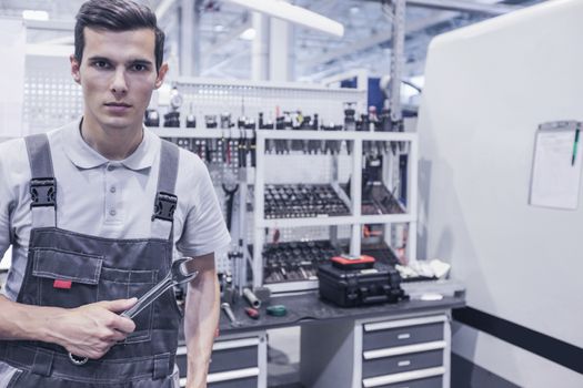 Mechanical technician worker at cnc milling plant workshop holding wrench