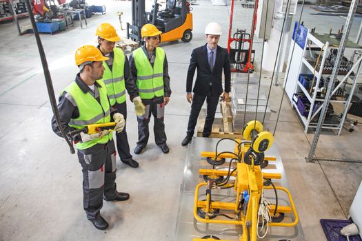 Group of workers and business man at facroty, permanent electro magnets for lifting steel plate, industrial lifting magnets, sheet lifting magnet loads sheet metal on shot blasting machine