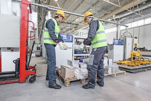 Two workers carry aluminium billet at CNC machine shop