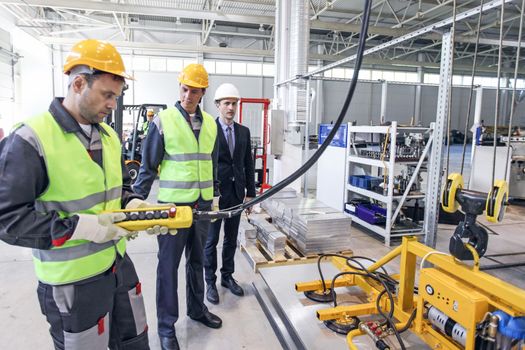 Group of workers and business man at facroty, permanent electro magnets for lifting steel plate, industrial lifting magnets, sheet lifting magnet loads sheet metal on shot blasting machine