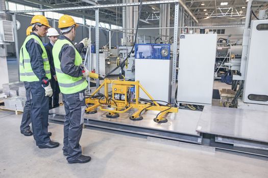 Group of workers and business man at facroty, permanent electro magnets for lifting steel plate, industrial lifting magnets, sheet lifting magnet loads sheet metal on shot blasting machine