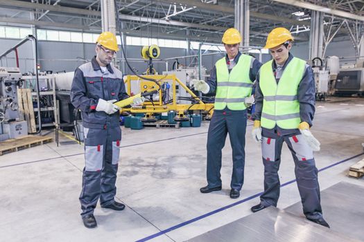 Group of workers and business man at facroty, permanent electro magnets for lifting steel plate, industrial lifting magnets, sheet lifting magnet loads sheet metal on shot blasting machine