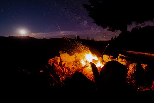 Atmospheric night around the campfire in the Black Forest with a super full moon and the Milky Way.