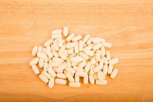 Many prescription, vitamin or supplement pills on a wood table