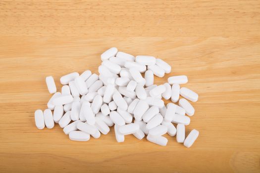 Many prescription, vitamin or supplement pills on a wood table