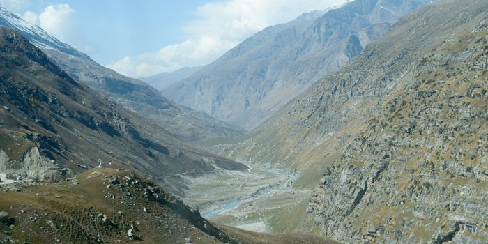 V-shaped Himalayas valley down which a river with a winding course flows. An interlocking overlapping spur hill ridges V-shaped valley that extends into a concave bend from opposite side of riverbank.