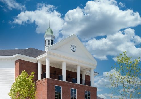 A nice commercial building of brick and siding with a clock and cupola