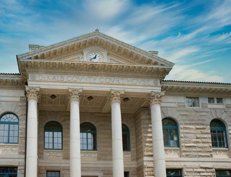 An old county courthouse of granite with columns under a nice sky