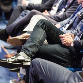 Row of unrecognizable business people sitting in conference hall at business event. Audience at business seminar. Business and Entrepreneurship concept.