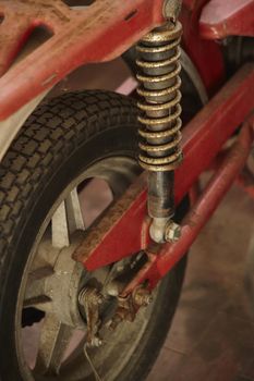 Detail of the rear wheel of a vintage red scooter with signs of wear and rust.