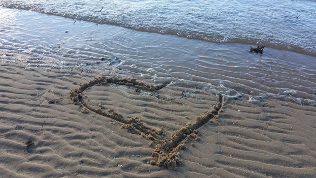 Drawing heart on the sand for Valentin day.