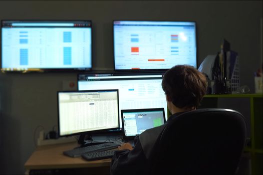 The hacker sits behind the monitor and works. The work of computer technician and programmer.