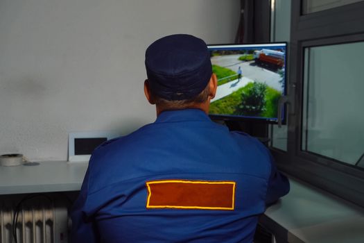 A security guard sits at the MONITOR of the CCTV camera.
