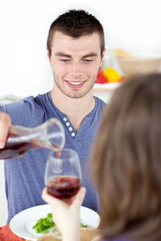 Attractive young man having dinner with his girlfriend drinking wine in the kitchen