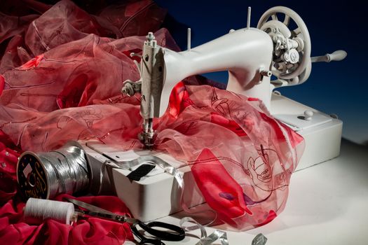 Sewing machine, fabric and scissors on a studio background