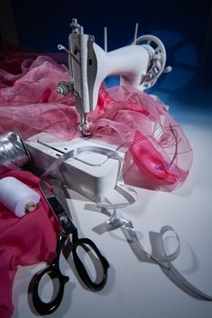 Sewing machine, fabric and scissors on a studio background