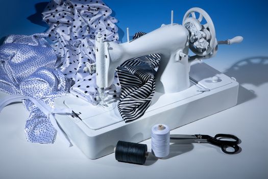 Sewing machine, fabric and scissors on a studio background