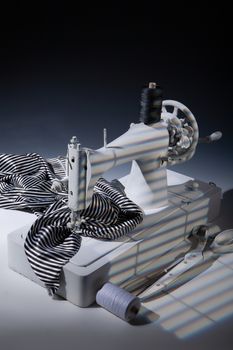 Sewing machine, fabric and scissors on a studio background