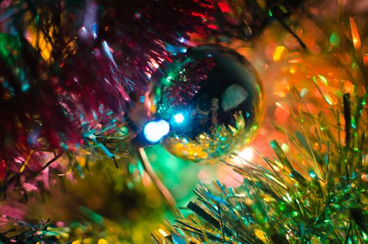 Photographers reflexion over a Christmas tree ball surrounded by colorful spumillion