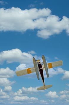 A yellow and white sea plane shot from below against blue sky