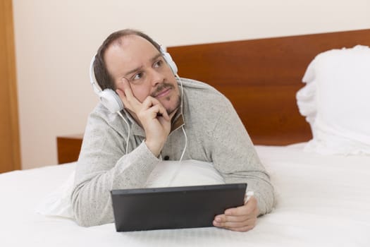 casual man working with a tablet pc in bed