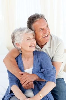 Senior couple hugging on their bed at home