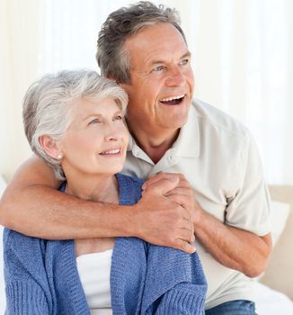 Senior couple hugging on their bed at home