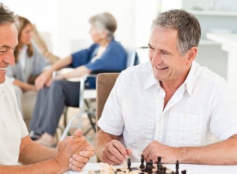 Men playing chess while their wifes are talking