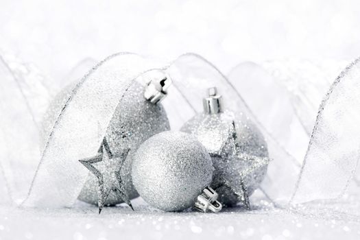 Christmas decorative balls and ribbon on silver glitter background