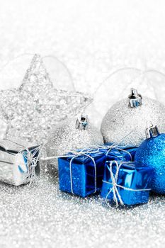 Christmas gifts and decoration on shiny silver glitter background