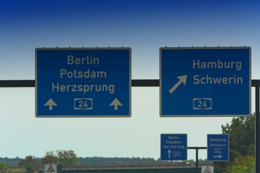 German motorway sign with inscription in German direction arrow to the cities - Berlin, Potsdam, Herzsprung, Hamburg and Schwerin