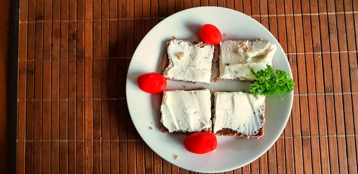 Homemade wholemeal brown bread with cottage cheese and parsley on brown bamboo base.