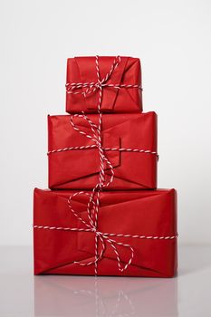 Christmas gift boxes wrapped in red paper and bow of dtriped rope on white background