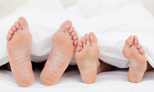 Two members of a family showing their feet while lying on a bed