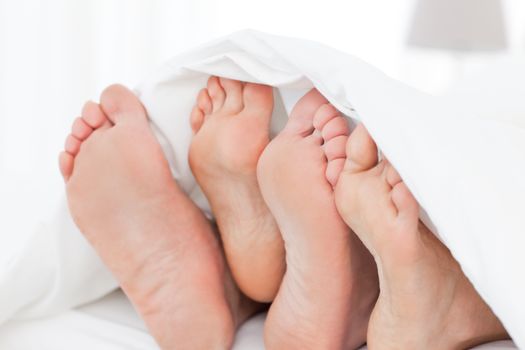 Two members of a family showing their feet while lying on a bed