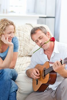 Romantic man playing guitar for her wife at home